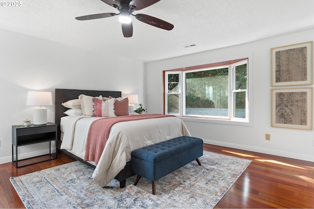 bedroom with ceiling fan, dark hardwood / wood-style floors, and a textured ceiling