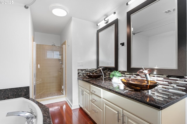 bathroom with wood-type flooring, plus walk in shower, decorative backsplash, and vanity