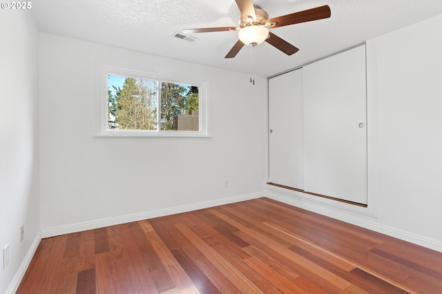 unfurnished room with hardwood / wood-style flooring, ceiling fan, and a textured ceiling