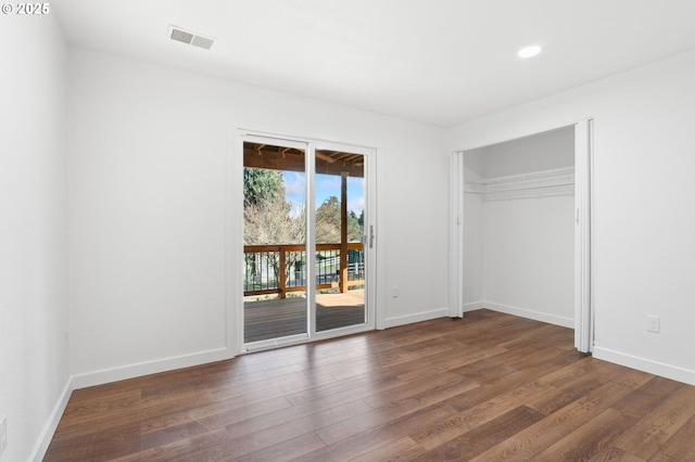 unfurnished bedroom featuring access to exterior, dark hardwood / wood-style flooring, and a closet