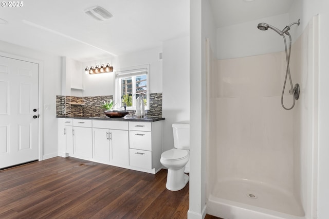 bathroom with walk in shower, toilet, tasteful backsplash, vanity, and hardwood / wood-style floors