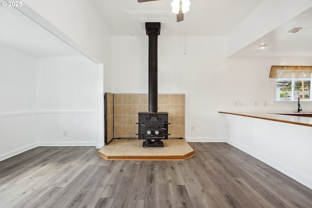 400 Mccoy St, Moro, OR 97039 - unfurnished living room featuring a wood stove, wood finished floors, baseboards, ceiling fan, and a sink
