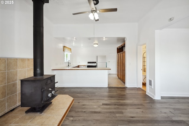 400 Mccoy St, Moro, OR 97039 - kitchen with a ceiling fan, a wood stove, wood finished floors, a sink, and freestanding refrigerator