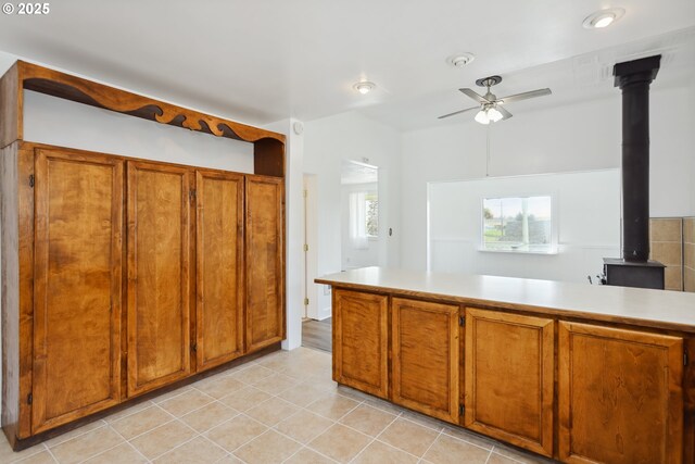 400 Mccoy St, Moro, OR 97039 - kitchen with brown cabinets, ceiling fan, a wood stove, light countertops, and light tile patterned floors