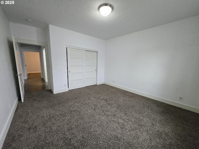 unfurnished bedroom featuring a closet, a textured ceiling, and dark colored carpet