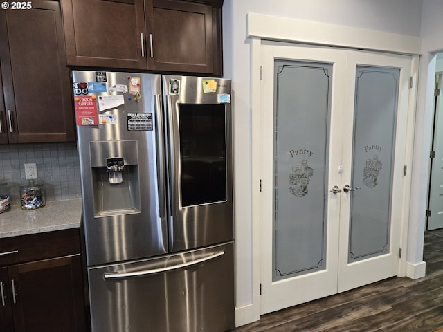 kitchen with light stone countertops, stainless steel refrigerator with ice dispenser, backsplash, dark hardwood / wood-style flooring, and dark brown cabinetry