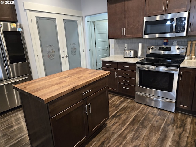 kitchen featuring stainless steel appliances, wooden counters, backsplash, and dark wood-type flooring