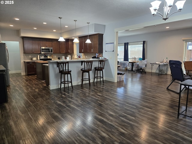 kitchen featuring a chandelier, decorative light fixtures, stainless steel appliances, decorative backsplash, and dark brown cabinets