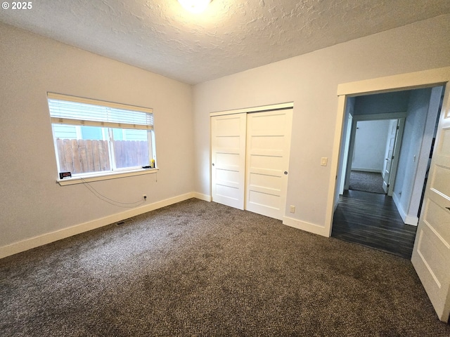 unfurnished bedroom featuring a textured ceiling, a closet, and dark carpet