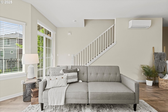 living area with a wall unit AC, wood finished floors, and baseboards