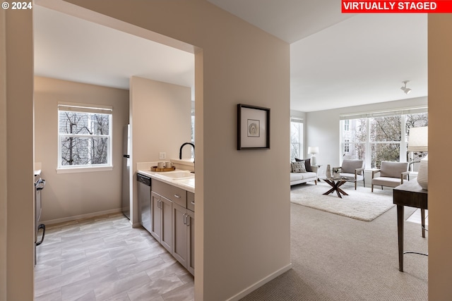 bar area with a sink, dishwasher, and baseboards