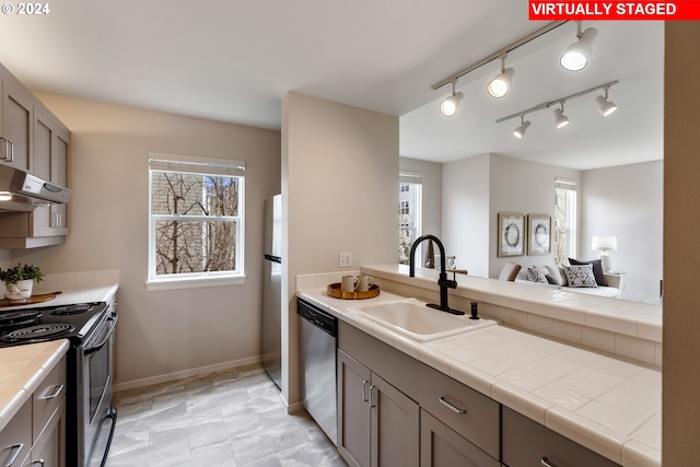 kitchen with a sink, stainless steel appliances, exhaust hood, and plenty of natural light
