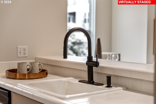 kitchen view of a sink, backsplash, and tile counters