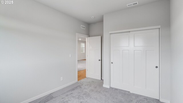 unfurnished bedroom featuring carpet flooring, baseboards, visible vents, and a closet