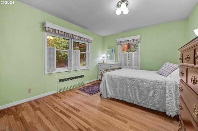 bedroom featuring radiator heating unit and hardwood / wood-style flooring