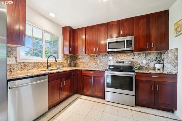 324 NE 108th Pl, Portland, OR 97220 - kitchen featuring stainless steel appliances, light stone counters, light tile patterned flooring, and decorative backsplash