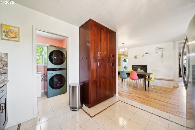 324 NE 108th Pl, Portland, OR 97220 - laundry area featuring stacked washer / drying machine, light tile patterned floors, a glass covered fireplace, and a chandelier