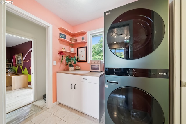 324 NE 108th Pl, Portland, OR 97220 - laundry area with stacked washer / dryer, cabinet space, and light tile patterned flooring