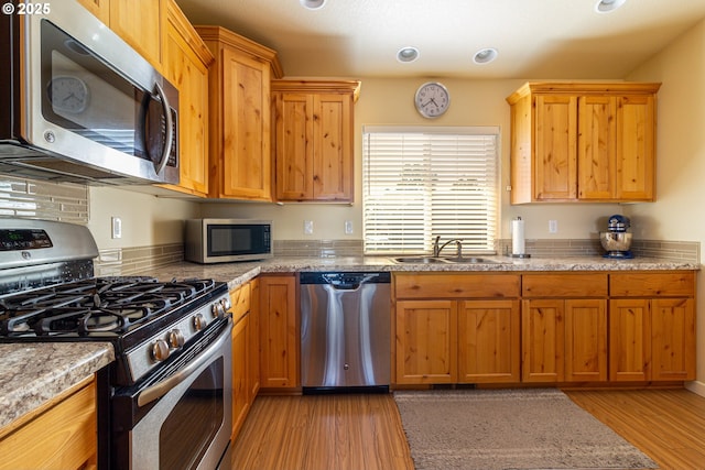 2260 NE 8th St, Hermiston, OR 97838 - kitchen with appliances with stainless steel finishes, light wood finished floors, decorative backsplash, and light stone countertops