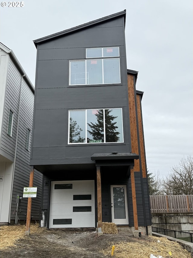 contemporary home featuring an attached garage and fence