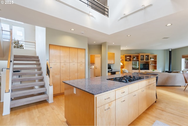 kitchen with light brown cabinetry, light wood-style flooring, a center island, and black gas cooktop