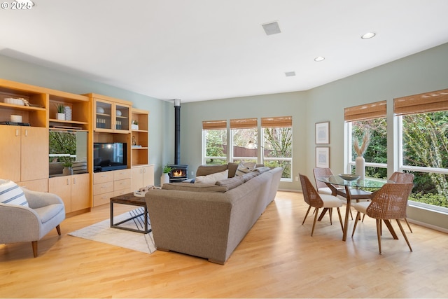 living room featuring visible vents, a wood stove, recessed lighting, and light wood-type flooring