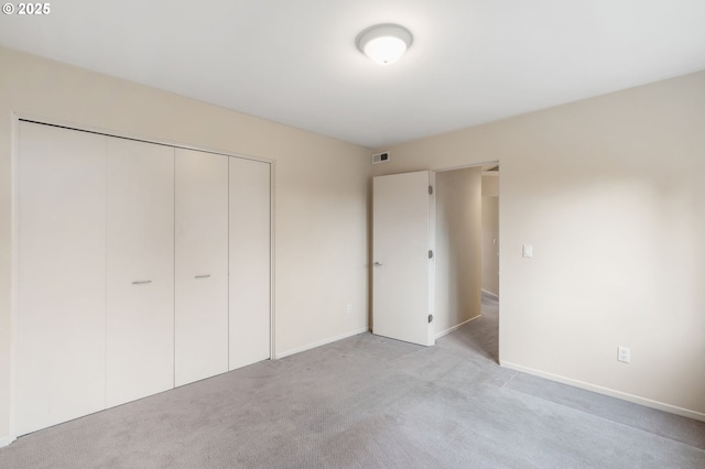 unfurnished bedroom featuring a closet, visible vents, light carpet, and baseboards