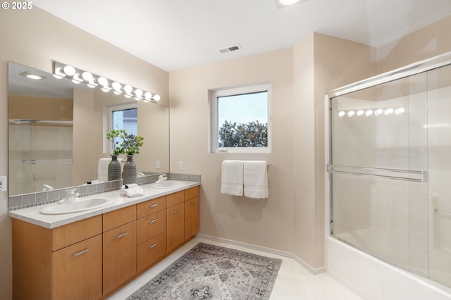 full bath featuring double vanity, visible vents, baseboards, and a sink