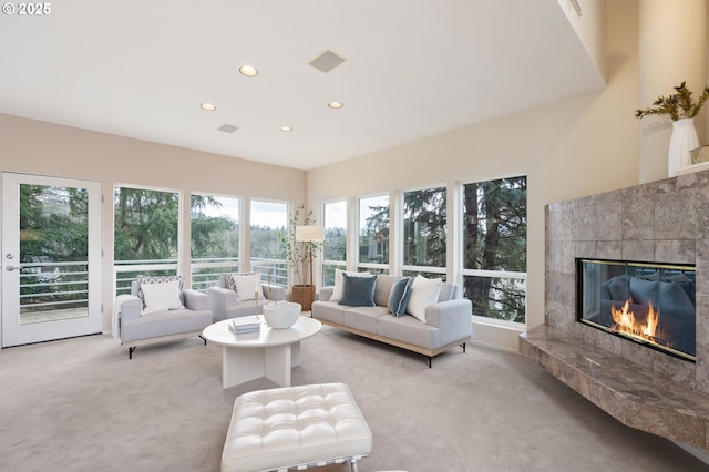 living area with a tiled fireplace, plenty of natural light, light colored carpet, and recessed lighting