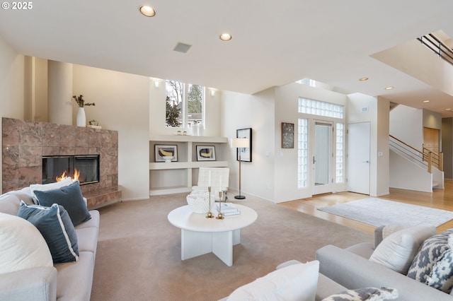 living area featuring recessed lighting, stairway, a premium fireplace, baseboards, and light colored carpet