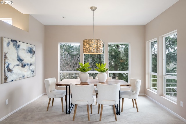 dining space with baseboards and light colored carpet