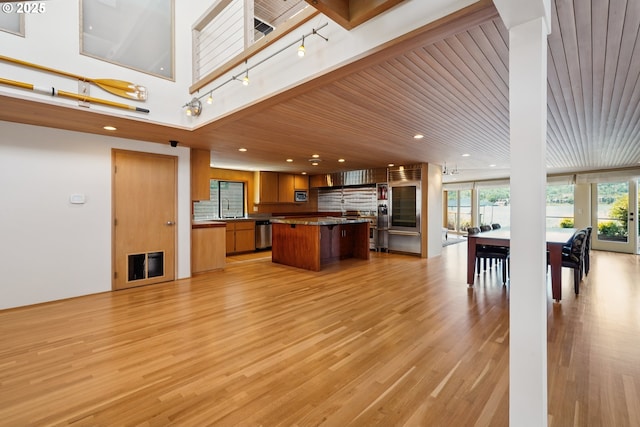 6901 SE Oaks Park Way Unit F, Portland, OR 97202 - kitchen featuring appliances with stainless steel finishes, a sink, brown cabinets, a kitchen island, and light wood-style flooring