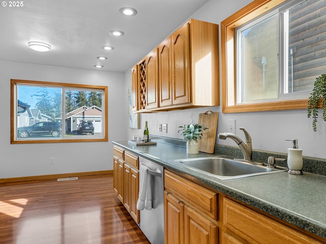 kitchen featuring dark wood-style flooring, dark countertops, stainless steel dishwasher, a sink, and baseboards