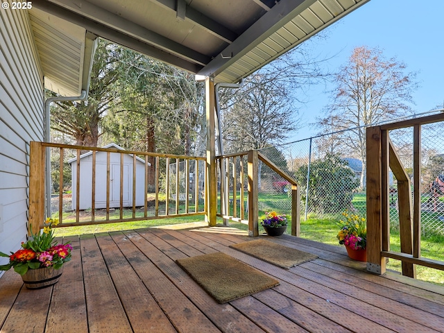 deck featuring a shed, fence, and an outbuilding