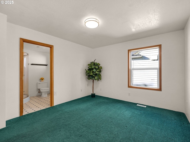 unfurnished bedroom featuring a textured ceiling, visible vents, connected bathroom, and carpet flooring