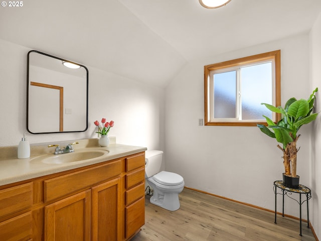 bathroom featuring lofted ceiling, toilet, wood finished floors, and vanity