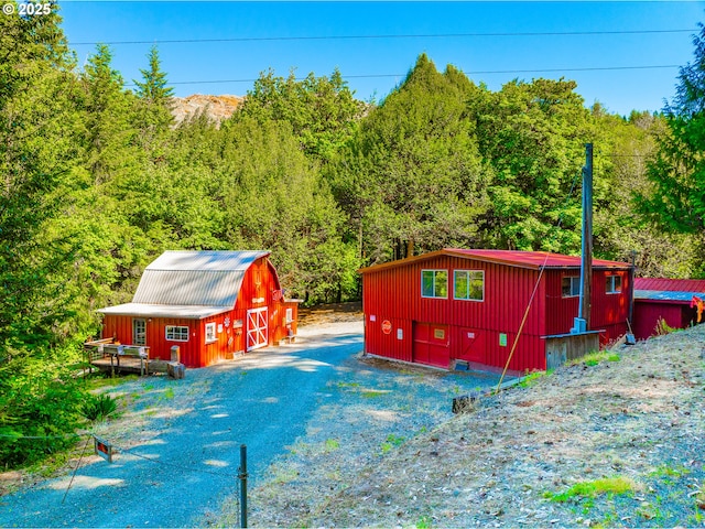 51256 Salmon Gulch Rd, Myrtle Point, OR 97458 - view of property exterior featuring a barn, a wooded view, and an outbuilding