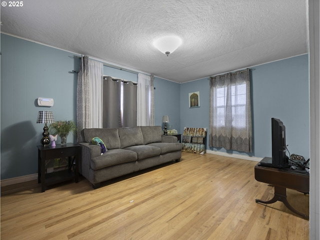 living room with a textured ceiling, baseboards, and wood finished floors