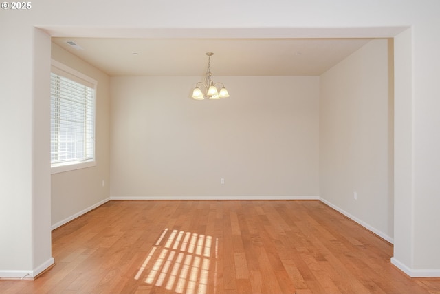 unfurnished room with a notable chandelier and light hardwood / wood-style floors