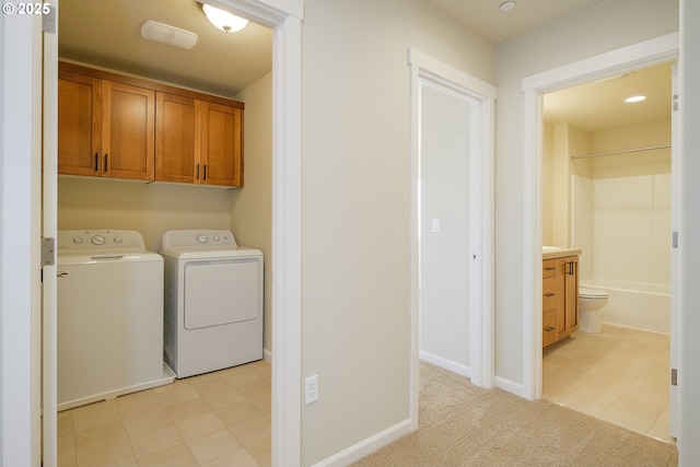 washroom featuring washing machine and clothes dryer, cabinets, and light carpet