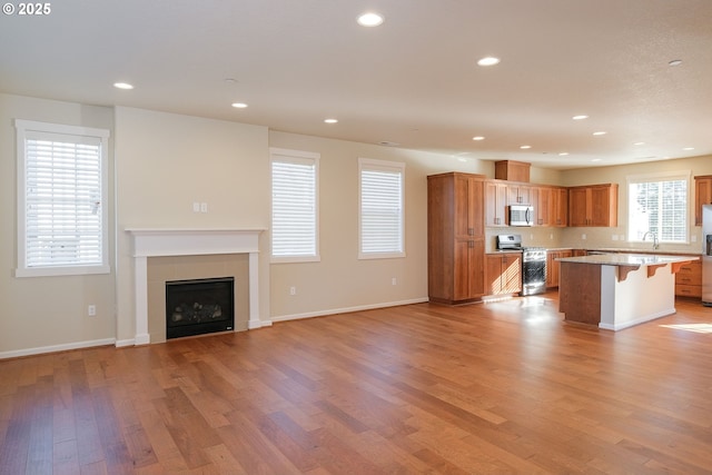 kitchen featuring a kitchen breakfast bar, appliances with stainless steel finishes, sink, a kitchen island, and light hardwood / wood-style floors