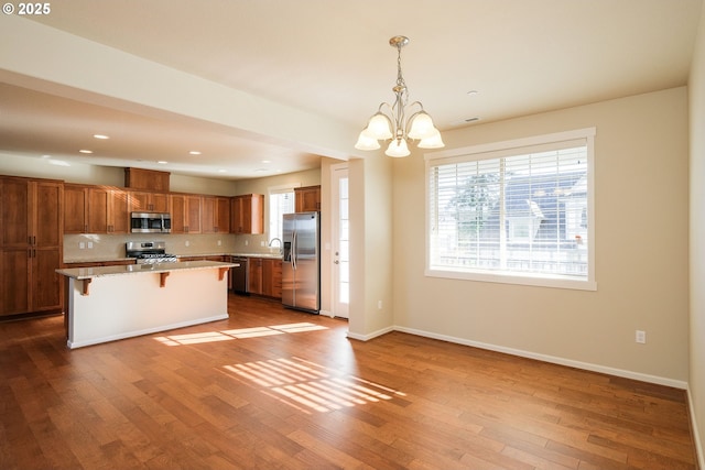 kitchen with a center island, appliances with stainless steel finishes, a kitchen breakfast bar, pendant lighting, and a healthy amount of sunlight