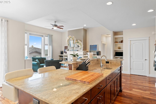 kitchen featuring ceiling fan, recessed lighting, dark wood-type flooring, a sink, and light stone countertops