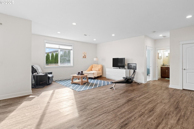 sitting room with baseboards, wood finished floors, and recessed lighting