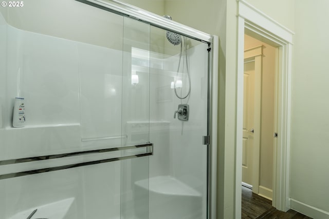 bathroom with a shower stall, baseboards, and wood finished floors