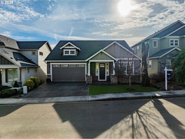 craftsman house featuring a garage, concrete driveway, stone siding, board and batten siding, and a front yard