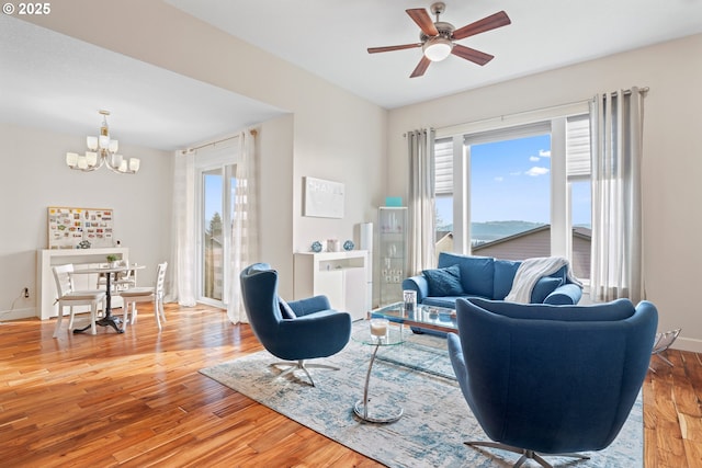 living room featuring baseboards, wood finished floors, and ceiling fan with notable chandelier