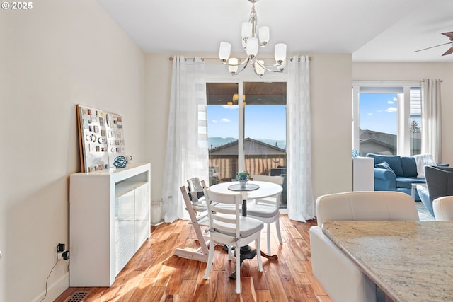 dining room featuring light wood finished floors and ceiling fan with notable chandelier