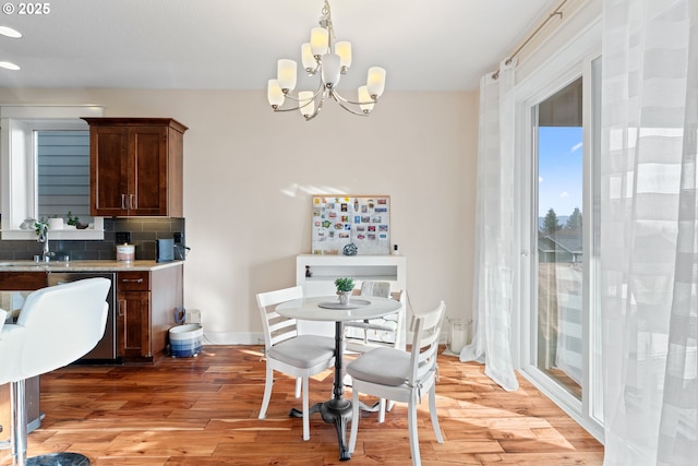 dining space with an inviting chandelier, light wood-style flooring, and baseboards