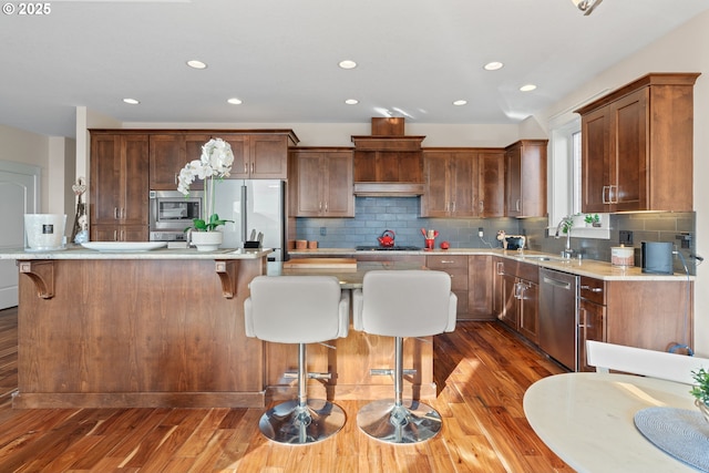 kitchen featuring appliances with stainless steel finishes, a sink, a kitchen bar, and wood finished floors